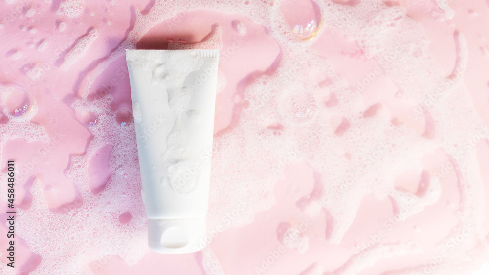 white cosmetic tube on a pink background with soap foam and bubbles. Face or body cleancer concept. Copy space white cosmetic tube on a pink background with soap foam and bubbles. Face or body cleancer concept. Copy space