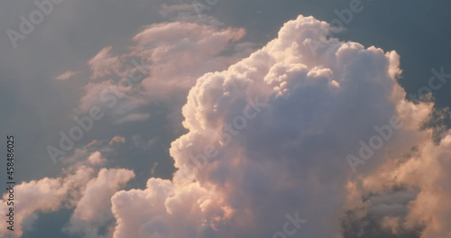 Pink fluffy cloud in heaven, stunning view of beautiful sunset cloudscape. View from airplane. Cinematic aerial foto of incredible cloud against blue sky in sunny day