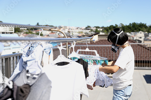 コロナ禍で、マスク姿で洗濯をする女性。