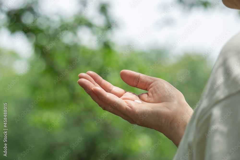 Hand of the elderly or middle-aged woman taking medicine in nature. 自然の中で薬を持つ高齢なまたは中高年の女性の手 Hand of the elderly or middle-aged woman taking medicine in nature. 自然の中で薬を持つ高齢なまたは中高年の女性の手