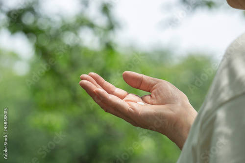 Hand of the elderly or middle-aged woman taking medicine in nature. 自然の中で薬を持つ高齢なまたは中高年の女性の手 © Kana Design Image