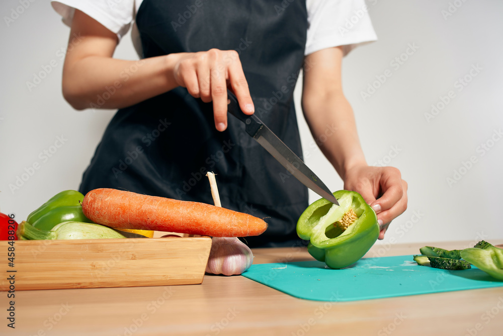 Woman in black apron cutting vegetables in the kitchen housewife preparing food Woman in black apron cutting vegetables in the kitchen housewife preparing food