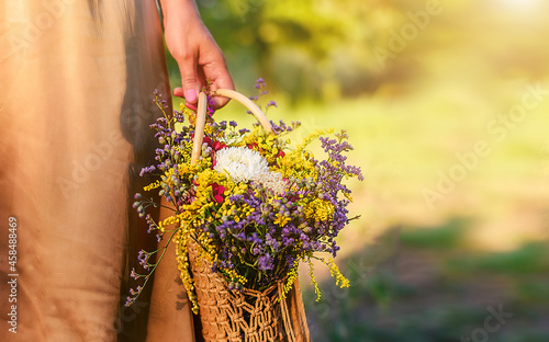 Beautiful wildflowers in the hands of a woman on a summer field. Summer mood