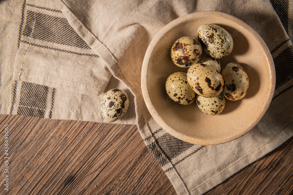 Fresh quail eggs on a ceramic bowl, brown wooden table. Raw quail eggs close-up on a culinary background. Concept of preparation for cooking Fresh quail eggs on a ceramic bowl, brown wooden table. Raw quail eggs close-up on a culinary background. Concept of preparation for cooking