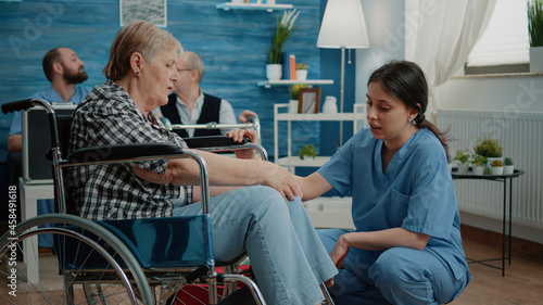 Old woman in nursing home receiving medical visit for checkup from nurse. Medical assistant doing consultation for patient with disability in wheelchair. Person with physical health issues