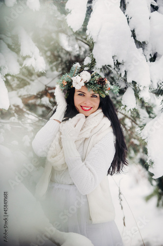 Portrait of a woman in white clothes in a cold winter forest. Girl with a wreath on her head in a snow-covered winter forest photo