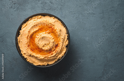 Oriental hummus with paprika and olive oil on a dark background. Vegetable, healthy, vegetarian food. Top view, copy space.