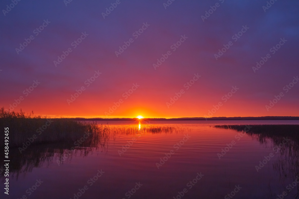 Red sunset over the lake with reflection in the water