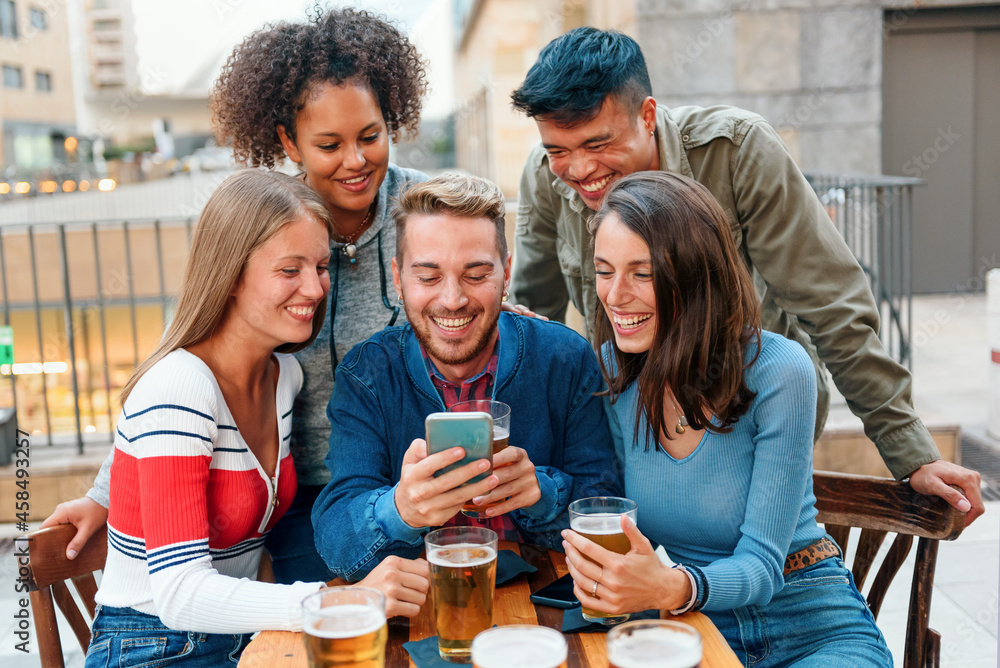 Obraz premium Group of diverse young friends gathered around a smartphone