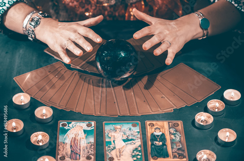 Tarot reader with tarot cards.Tarot cards face down on table near burning candles and crystal ball. photo