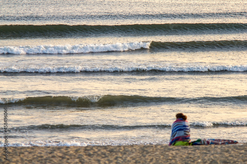 Junge Frau schaut in die Wellen des Ozeans, Atlantik, Wellen, Strand
