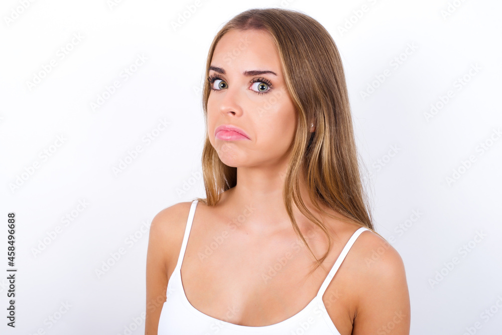 beautiful blonde girl wearing sexy t-shirt on white background with snobbish expression curving lips and raising eyebrows, looking with doubtful and skeptical expression, suspect and doubt. beautiful blonde girl wearing sexy t-shirt on white background with snobbish expression curving lips and raising eyebrows, looking with doubtful and skeptical expression, suspect and doubt.