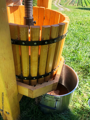 A cooking pot catches fresh cider as it streams from the wooden press. photo