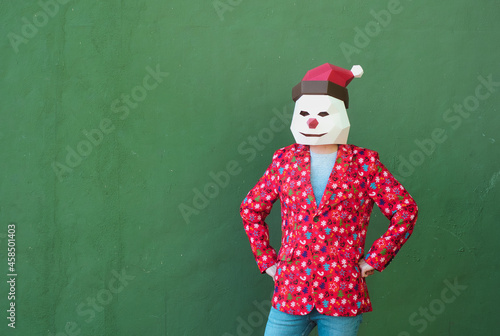 Anonymous person dressed in a christmas clothes and mask in a green background