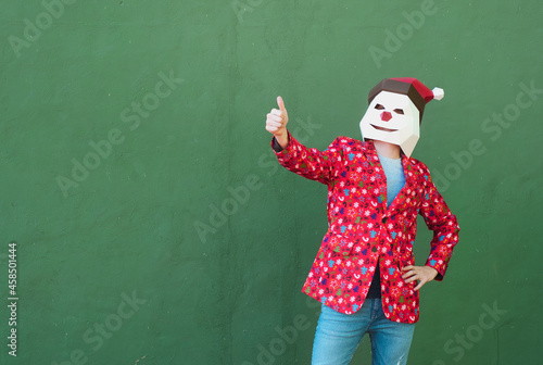 Anonymous person dressed in a christmas clothes and mask gesturing to be fine with the finger up