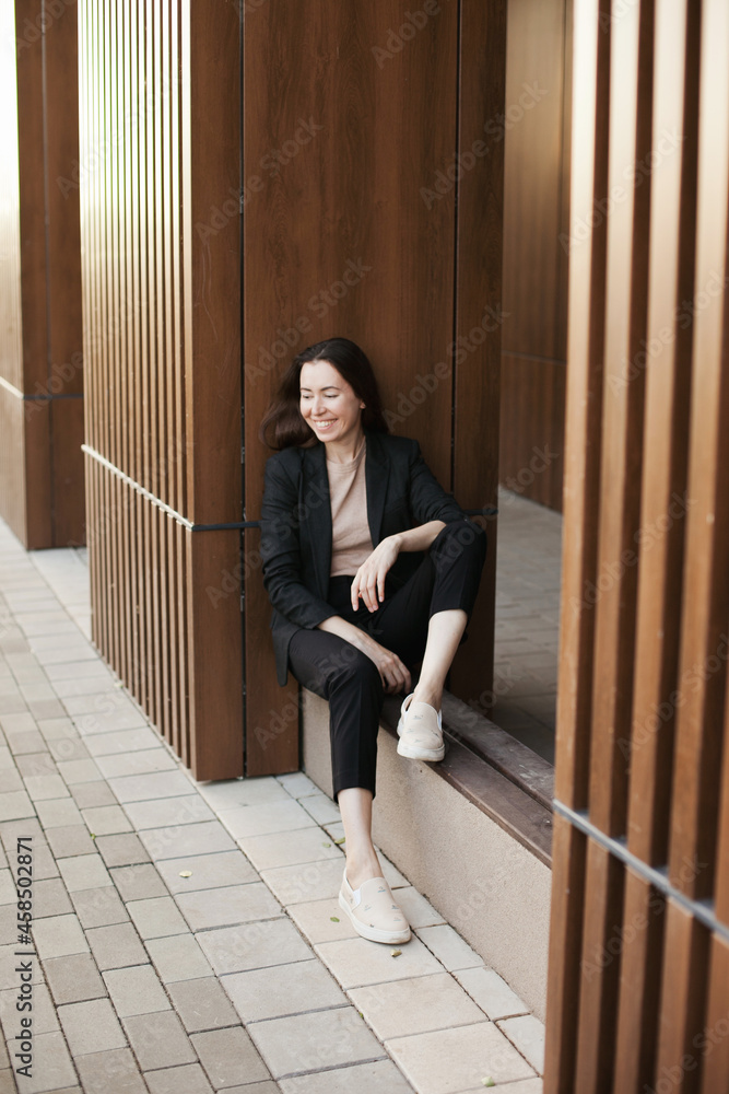 Young millennial businesswoman sitting by the office building Young millennial businesswoman sitting by the office building