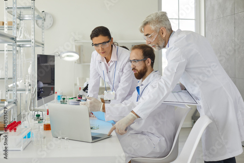 Group of researchers discuss the research with senior male supervisor in the laboratory. Scientists discuss the results of tests after a scientific experiment by recording all the data in a laptop.