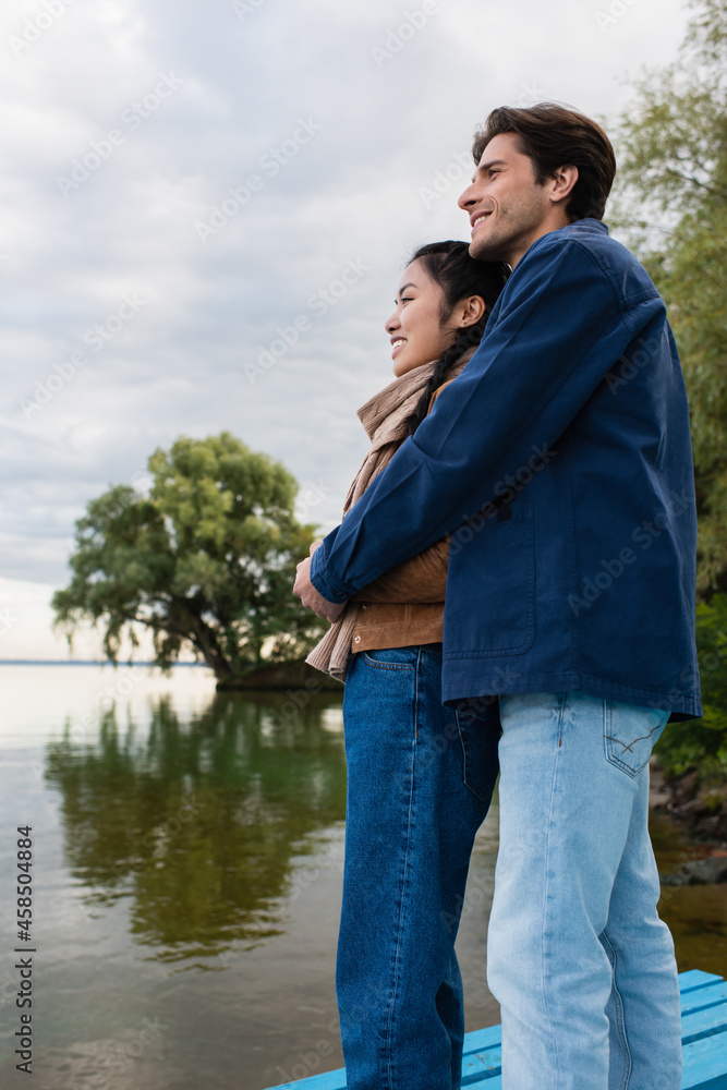 Side view of young multiethnic couple embracing near lake