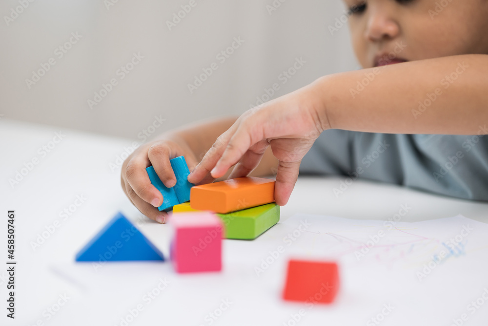Close up Children hand Practice the skills of playing with wooden toys on the table in living room. Asian little boy education from home. Developing children's learning before entering kindergarten Close up Children hand Practice the skills of playing with wooden toys on the table in living room. Asian little boy education from home. Developing children's learning before entering kindergarten