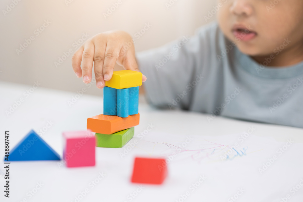Close up Children hand Practice the skills of playing with wooden toys on the table in living room. Asian little boy education from home. Developing children's learning before entering kindergarten Close up Children hand Practice the skills of playing with wooden toys on the table in living room. Asian little boy education from home. Developing children's learning before entering kindergarten