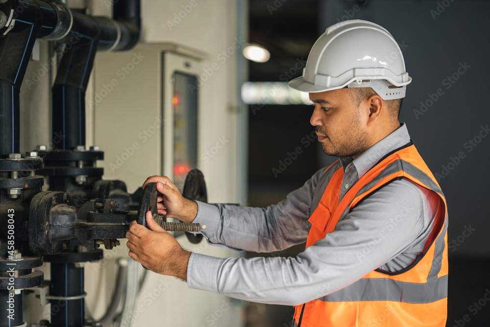 Young asian engineer working at valve water pump checking and maintenance for the safety. Worker control the system water of the building. Young asian engineer working at valve water pump checking and maintenance for the safety. Worker control the system water of the building.