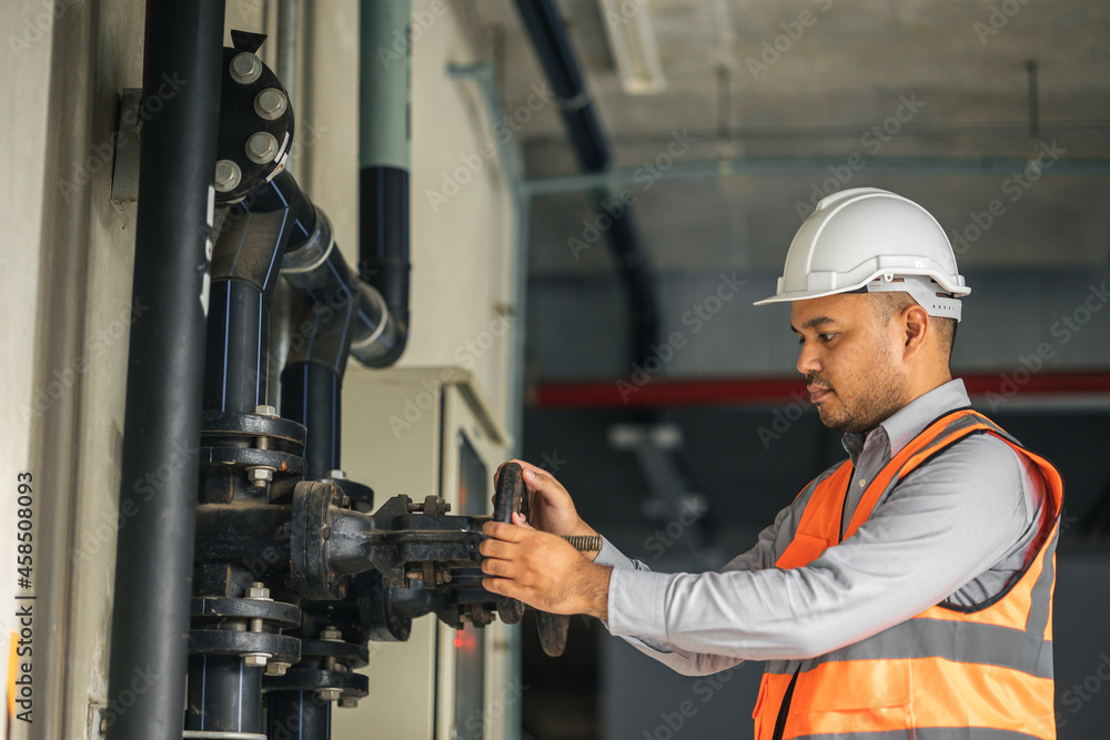 Young asian engineer working at valve water pump checking and maintenance for the safety. Worker control the system water of the building. Young asian engineer working at valve water pump checking and maintenance for the safety. Worker control the system water of the building.