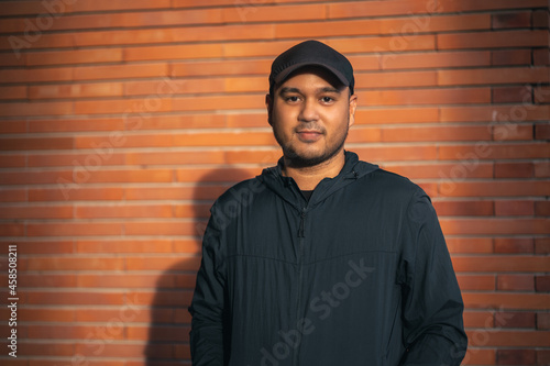 Young handsome asian man wearing sportswear standing post under the building urban city running outdoor. Portraits of Indian man jogging on the road. Training athlete outdoor concept.