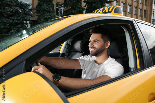 Handsome taxi driver in car on city street photo