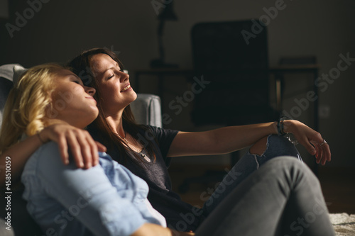 Young happy lesbians couple sitting on a sofa and they are hugging