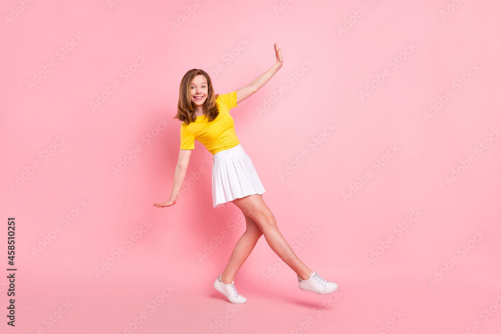 Full size profile side photo of young girl happy positive smile go walk playful isolated over pink color background Full size profile side photo of young girl happy positive smile go walk playful isolated over pink color background