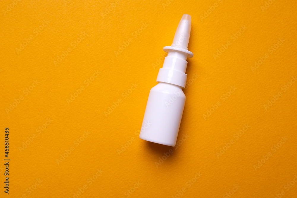 Bottle of nose drops on a yellow background close-up. Spray for the nose. View from above Bottle of nose drops on a yellow background close-up. Spray for the nose. View from above