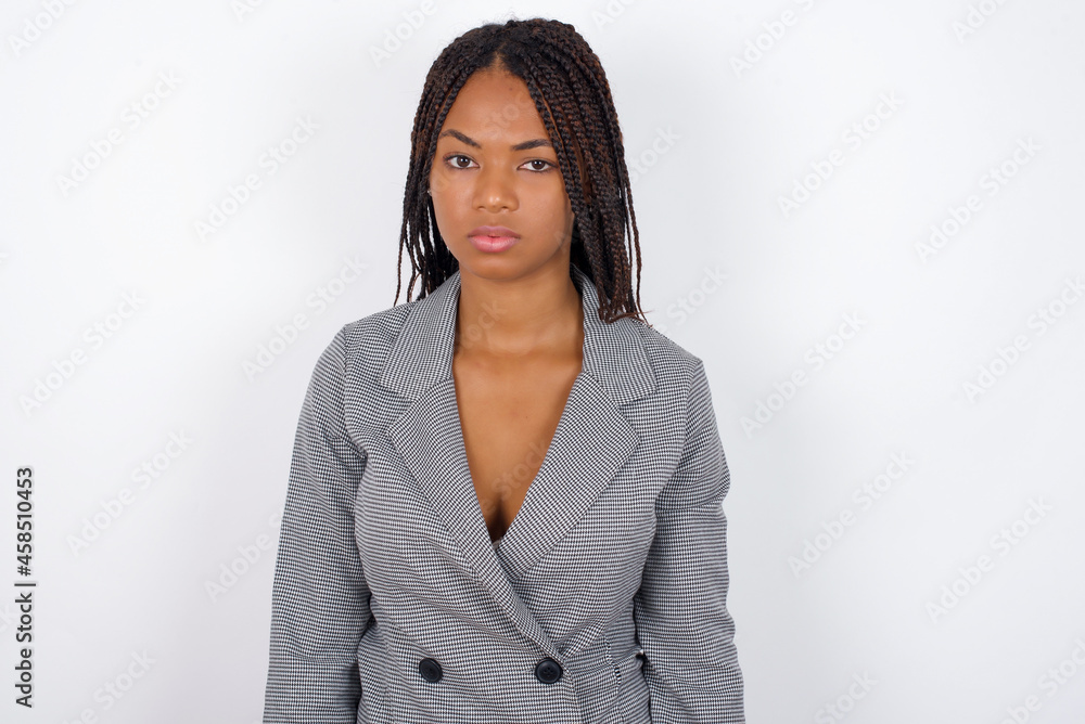 Φωτογραφία Young African American businesswoman with braids on white wall frowning his eyebrows being displeased with something