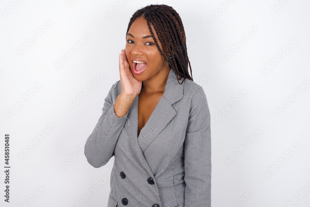 Shocked, astonished Young African American businesswoman with braids on white looking surprised in full disbelief wide open mouth with hand near face. Positive emotion facial expression body language. Shocked, astonished Young African American businesswoman with braids on white looking surprised in full disbelief wide open mouth with hand near face. Positive emotion facial expression body language.
