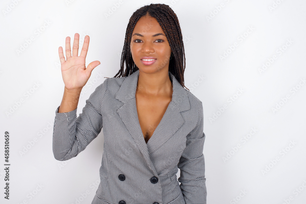 Young African American businesswoman with braids on white wall showing and pointing up with fingers number five while smiling confident and happy. Young African American businesswoman with braids on white wall showing and pointing up with fingers number five while smiling confident and happy.
