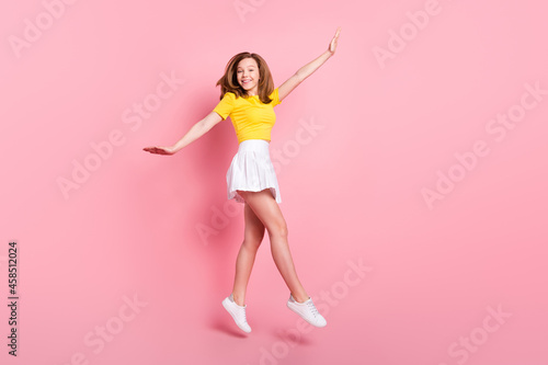 Full size profile side photo of young excited girl happy positive smile jump go walk isolated over pink color background