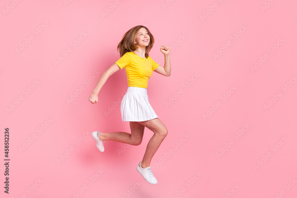 Full size profile side photo of young girl happy smile jump up go walk run isolated over pink color background Full size profile side photo of young girl happy smile jump up go walk run isolated over pink color background