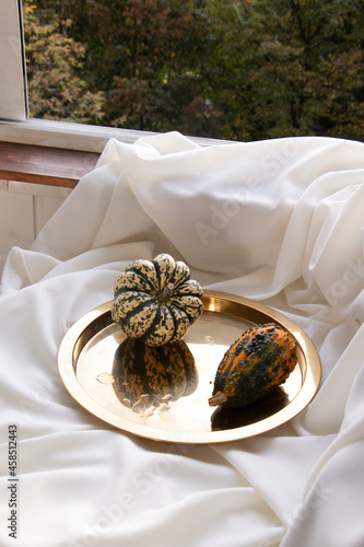 Small green and orange pumpkins on a golden tray