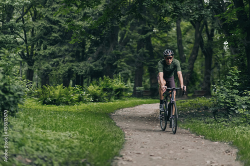 Muscular man cycling along city park during morning time