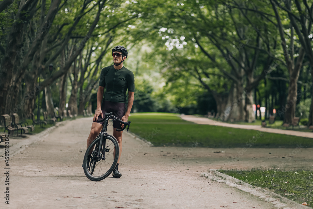 Muscular cyclist in helmet relaxing after ride outdoors