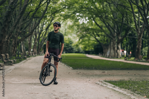 Fototapeta Naklejka Na Ścianę i Meble -  Muscular cyclist in helmet relaxing after ride outdoors
