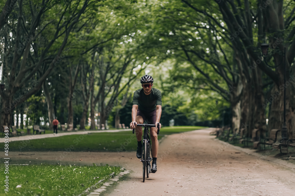Caucasian man in sport clothes riding bike at green park Caucasian man in sport clothes riding bike at green park