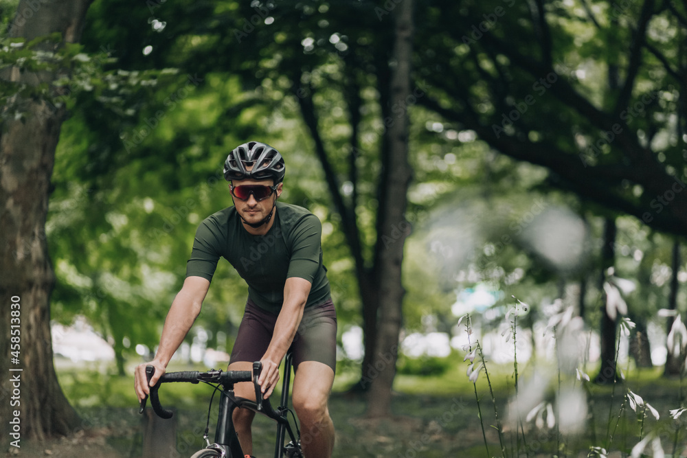 Man in helmet and glasses using bike for training outdoors Man in helmet and glasses using bike for training outdoors