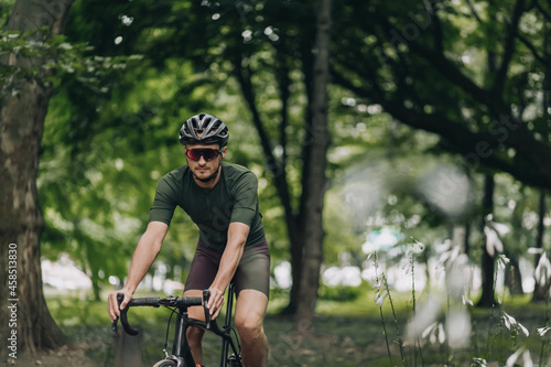 Man in helmet and glasses using bike for training outdoors