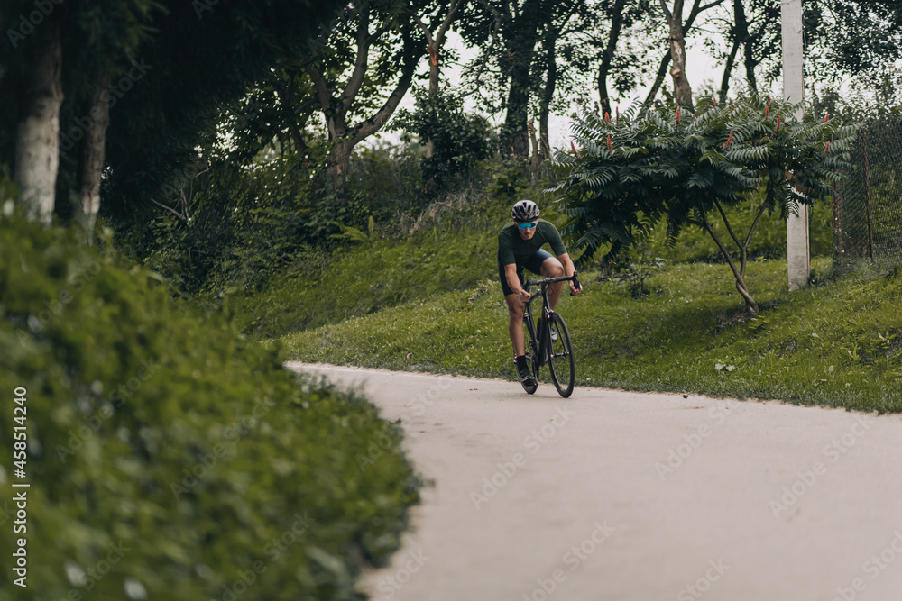 Muscular sportsman in helmet riding bike outdoors Muscular sportsman in helmet riding bike outdoors