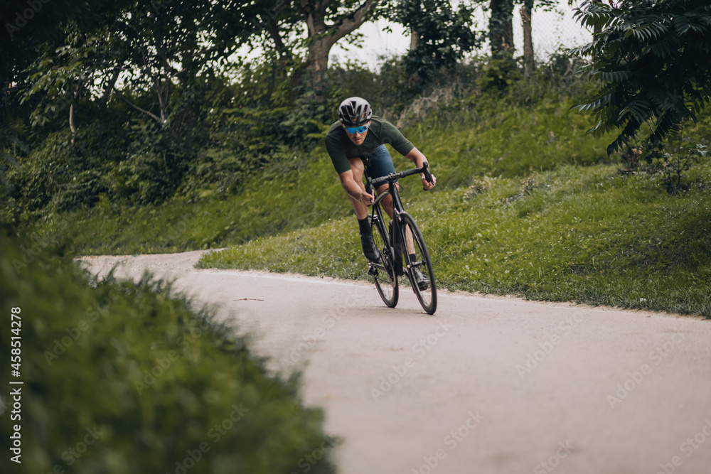 Man with muscular cycling alone at green city park