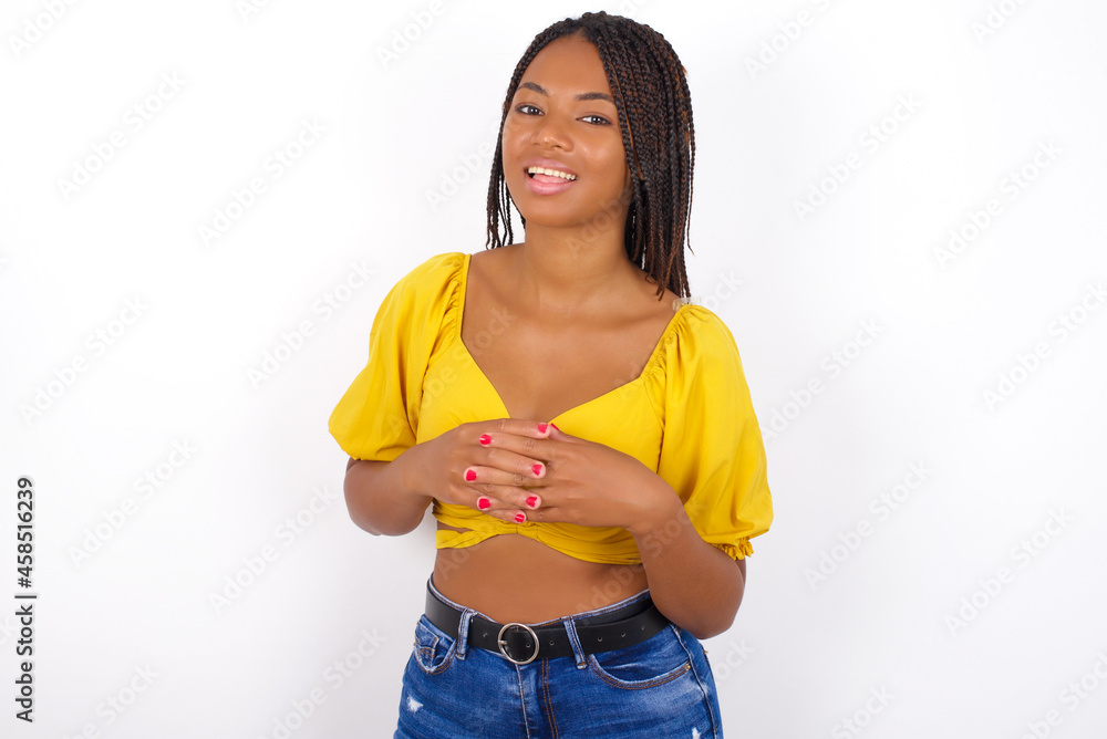 Smiling afro american woman with braids wearing sexy yellow t-shirt on white wall friendly and happily holding mobile phone taking selfie in mirror. Smiling afro american woman with braids wearing sexy yellow t-shirt on white wall friendly and happily holding mobile phone taking selfie in mirror.
