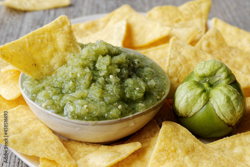 Green tomatillo salsa (salsa verde cruda) with corn tortilla chips nachos. photo