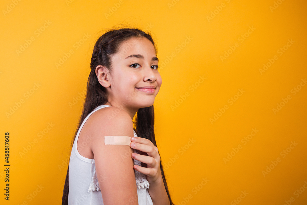 Obraz premium Smiling little girl after having received a vaccination on yellow background.