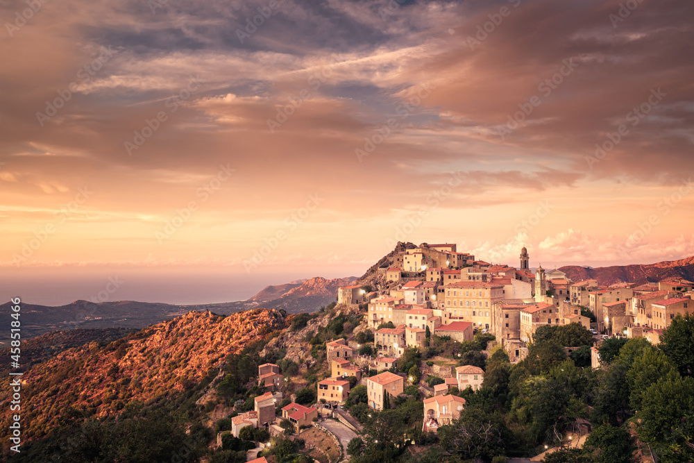 Sun setting on the remote mountain village of Speloncato in the Balagne region of Corsica with the Mediterranean sea in the distance