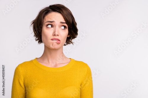 Photo of stressed brunette millennial lady bite lip look empty space wear yellow shirt isolated on grey color background © deagreez